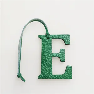 Green leather letter E bag charm detail shot, stylish alphabet pendant accessory for handbags.