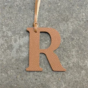 Leather R letter bag charm detail view, chic brown alphabet pendant with strap hanging.