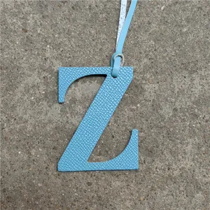 Detalle de primer plano de un colgante de bolso con letra Z de cuero azul con correa.