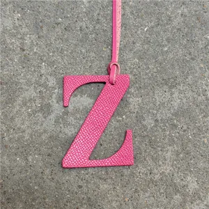 Vista detallada del colgante de bolso letra Z de cuero rosa con textura fina y correa colgante.