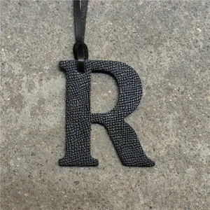 Black leather alphabet R bag charm pendant with strap, stylish accessory for purses and bags.