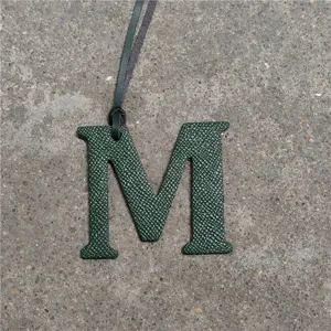 Leather letter M bag charm close up detail view green texture accessory decorative item