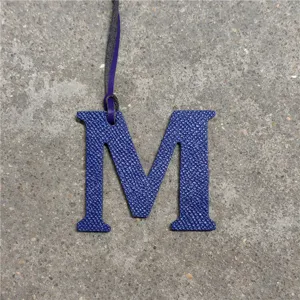 Blue leather letter M bag charm detail view, elegant initial charm for handbags and car keychains.