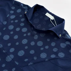 Détail de chemise à manches courtes jacquard bleu foncé, col avec étiquette, texture douce.