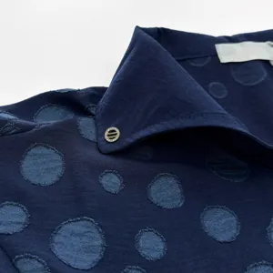Gros plan détaillé d'un haut de vêtement d'intérieur bleu foncé en jacquard à pois fins.