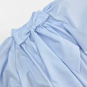 Close-up detail of the elegant light blue shirt collar featuring a large decorative bow tie.