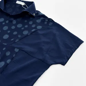 Détail de chemisier jacquard bleu foncé à manches courtes, tissu à pois, style chic.