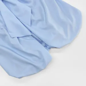 Close-up view of light blue women shirt fabric showing elegant bow tie collar detail.