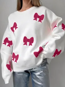 Nahaufnahme des weißen Strickpullovers mit verspielten rosa Schleifen und lockerer Passform.