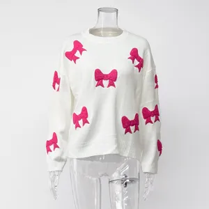 Weißes Strickpullover Detail mit rosa Schleifen und weicher Ärmeltextur im Herbst.