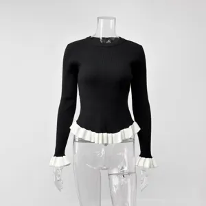 Detailaufnahme eines schwarzen Pullovers mit weißen Rüschen an Bündchen und Saum langärmelig.