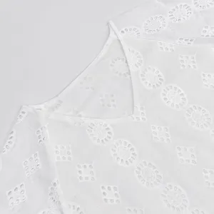 Gros plan sur les détails d'une robe blanche en coton col V avec broderie anglaise délicate.