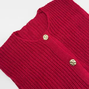 Nahaufnahme Detailansicht einer roten grobgestrickten ärmellosen Strickjacke mit Knöpfen.