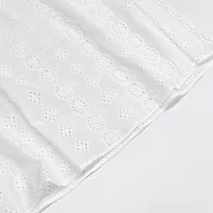 Détail de robe brodée anglaise blanche montrant une texture de coton française élégante.