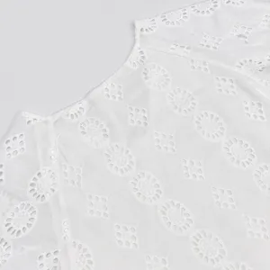 Vue détaillée du tissu en coton blanc brodé de trous, mettant en valeur un design ajouré.