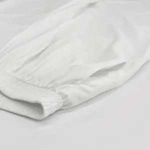 Close-up detail of white casual pants elastic waistband and pocket stitching, smooth fabric.