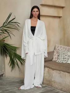 Detail view of the loose white tie-cardigan and trousers lounge set in a cozy neutral room.