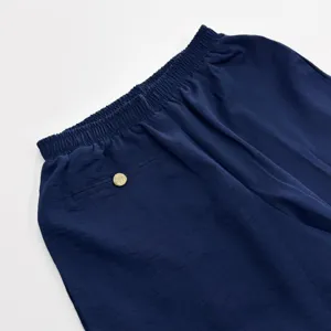 Détail de pantalon de détente, taille élastique bleu marine avec bouton doré.