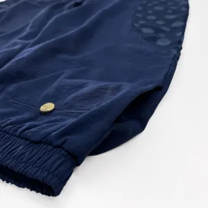Detail de pantalon de détente bleu marine avec taille élastique et bouton doré élégant.