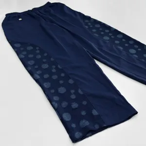 Détail de pantalon bleu marine avec empiècements latéraux en jacquard à pois et taille élastique.