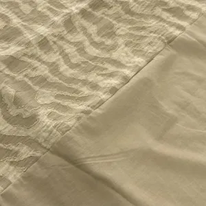 Gros plan sur le tissu d'un ensemble avec motif texturé et empiècement uni et lisse.