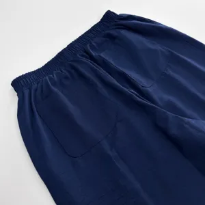 Gros plan sur les détails du pantalon bleu foncé, taille élastique et poches dos.
