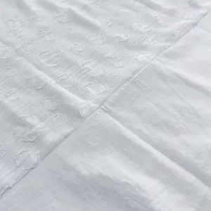 Vue rapprochée du tissu blanc de qualité supérieure avec des points brodés texturés.