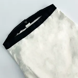 Close-up detail of linen long dress upper part with black contrast trim and button design.