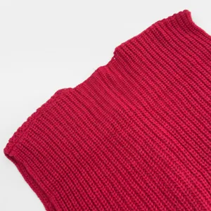 Detailed view of red chunky knit sleeveless cardigan texture and ribbed pattern design.