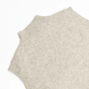 Vista detallada de chaleco de punto sin mangas minimalista con cuello alto en beige neutro.