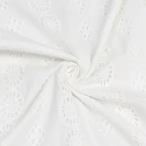 Gros plan sur le tissu en coton blanc pur brodé de délicats motifs ajourés circulaires.