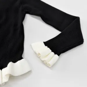 Schwarzes Strickoberteil Ärmel- und Bündchendetail mit kontrastierenden weißen Rüschen.