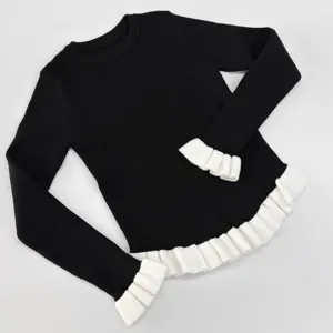 Detailansicht des schwarzen Strickpullovers mit kontrastierenden weißen Rüschenbündchen.