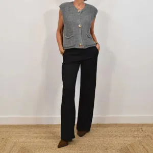 Detailed view of grey chunky knit sleeveless cardigan vest with buttons and pockets.