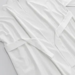 Vista dettagliata del cardigan lungo bianco casual con consistenza del tessuto e cintura.