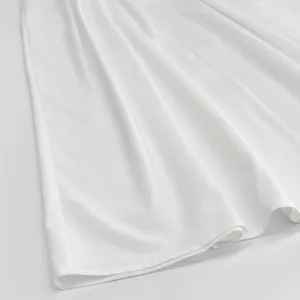 Primo piano di tessuto bianco che mostra una consistenza morbida e un drappeggio estivo.