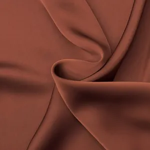Détail de tissu satiné marron, texture lisse luxueuse pour design de vêtement d'été élégant.