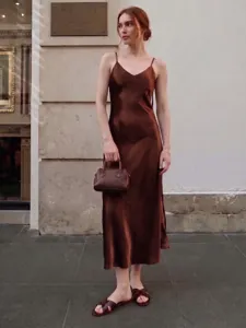 Détail de robe nuisette en satin de soie, robe midi marron élégante en style de rue.
