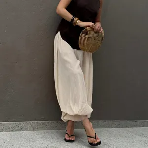 Detailed view of casual lightweight balloon trousers worn with a chic dark top and bamboo bag.