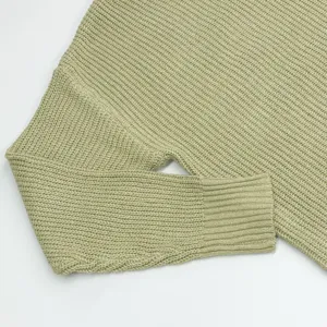 Close up view of women light green knitted sweater sleeve, soft ribbed texture material detail.