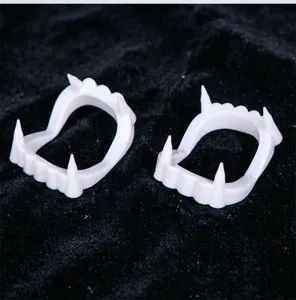 White plastic vampire fangs teeth props for Halloween party costume dress up accessories detail view