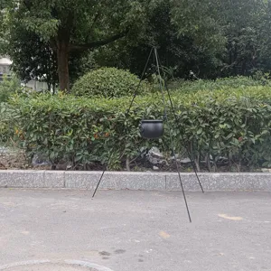 Detail view of outdoor Halloween black hanging witch cauldron with metal tripod stand setup.