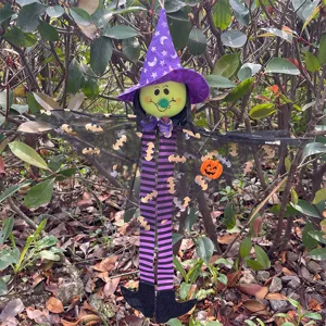 Halloween witch hanging decoration with striped legs and bat wings for holiday party prop.