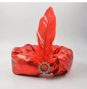 Roter metallischer Stoffturban mit lebendiger Feder und funkelnder Strass-Brosche.
