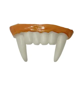 Close-up detail of white vampire teeth with orange gum line, Halloween party novelty prop.