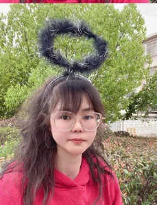 Black feather halo headband detail showing fluffy texture and silver sparkles for cosplay.