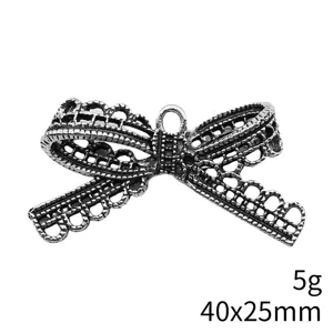Detailed view of antique silver bow pendant charm, hollow lace metal design, close-up texture.
