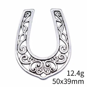 Close-up detail of vintage silver hollow horseshoe pendant, intricate scroll filigree design.