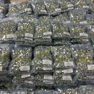 Detailed view of bulk crystal AB flatback rhinestones in small packs for nail art decoration.