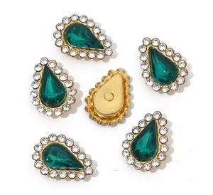Close-up detail of teardrop green acrylic rhinestone claw drill buttons for DIY crafts.